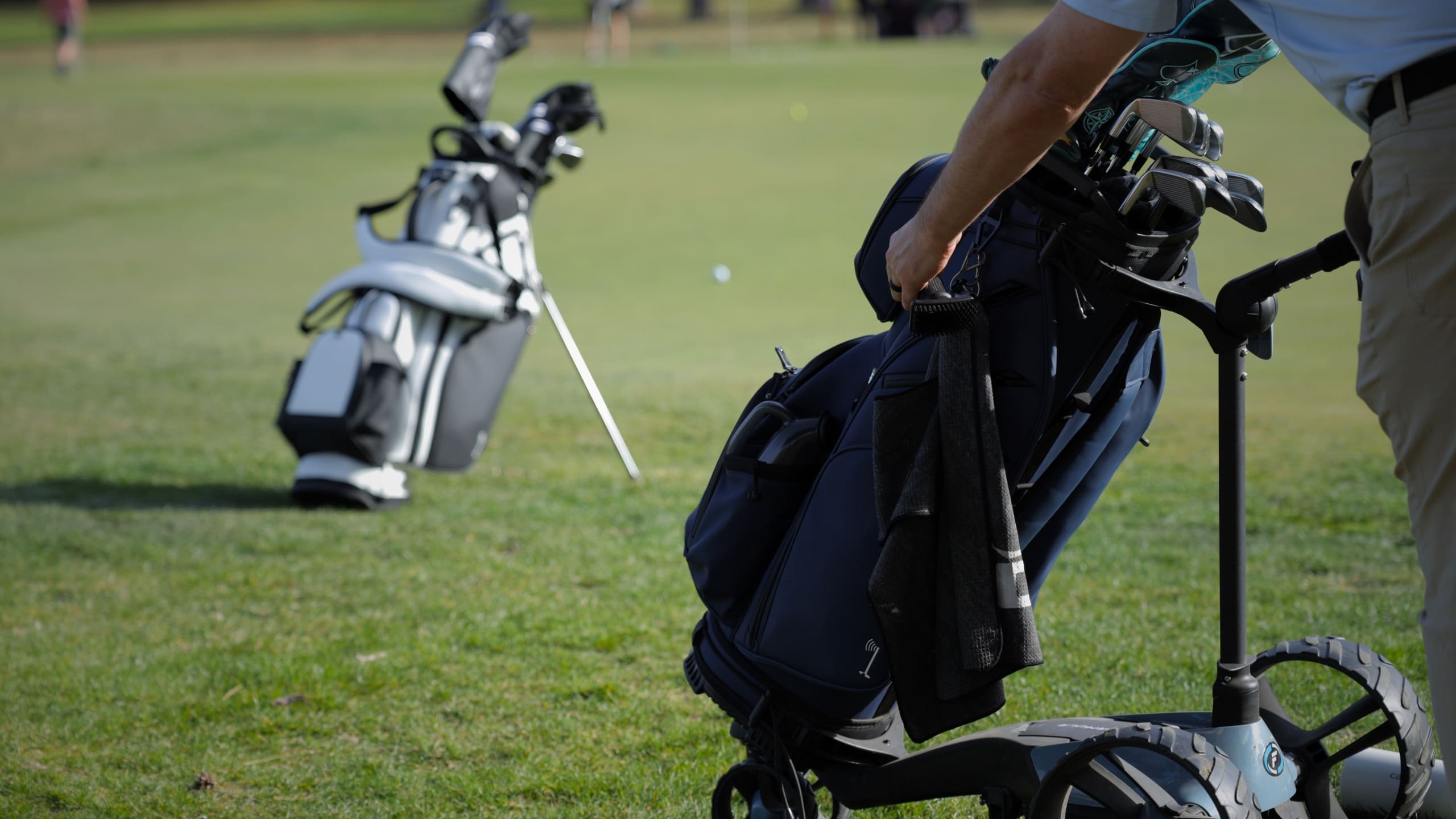 Golfer practices on green with Cart Tek Formula Remote electric cart and luxury golf cart bag with 14-way divider and ample storage.