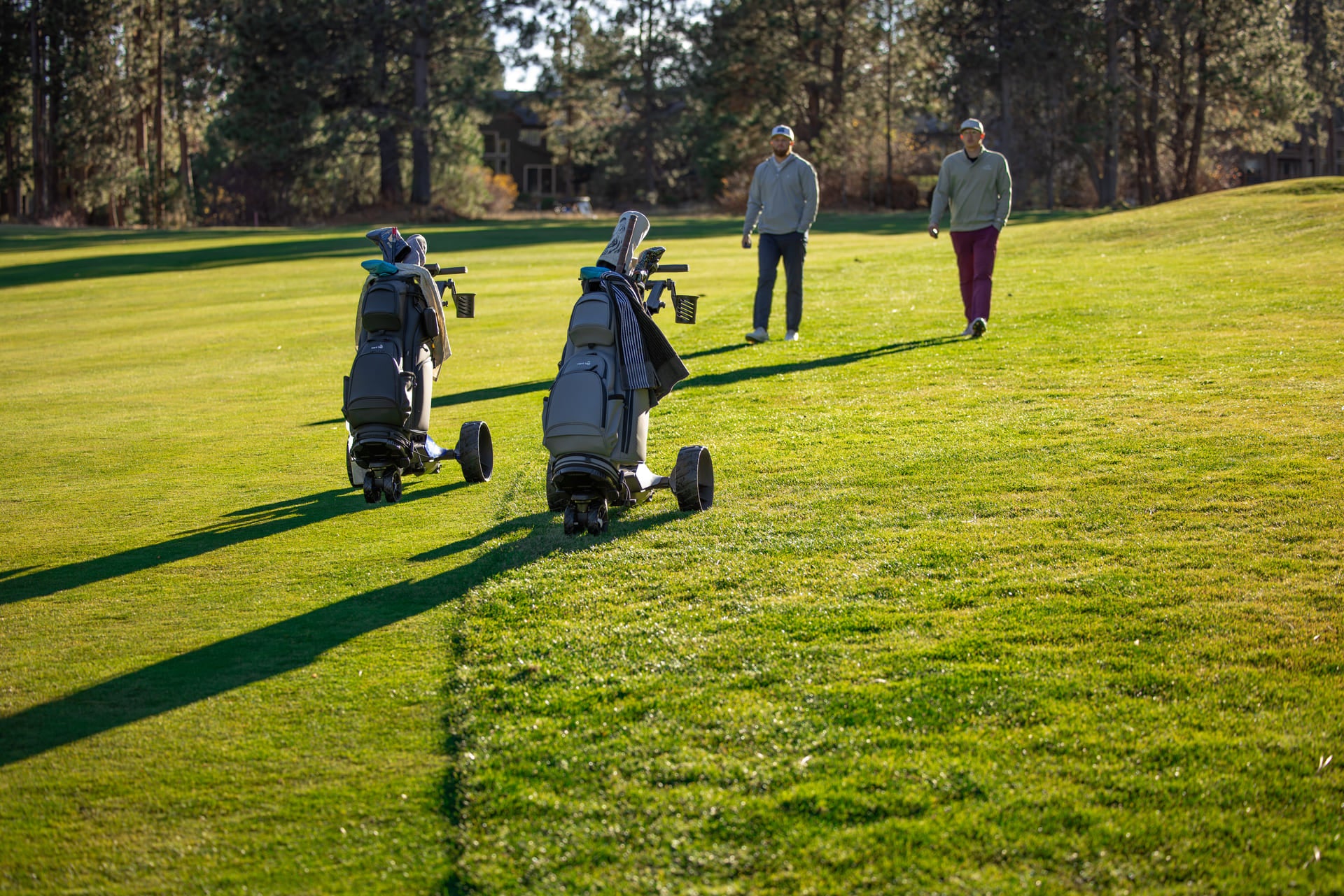 Two male walking golfers behind the best electric golf caddies in the US