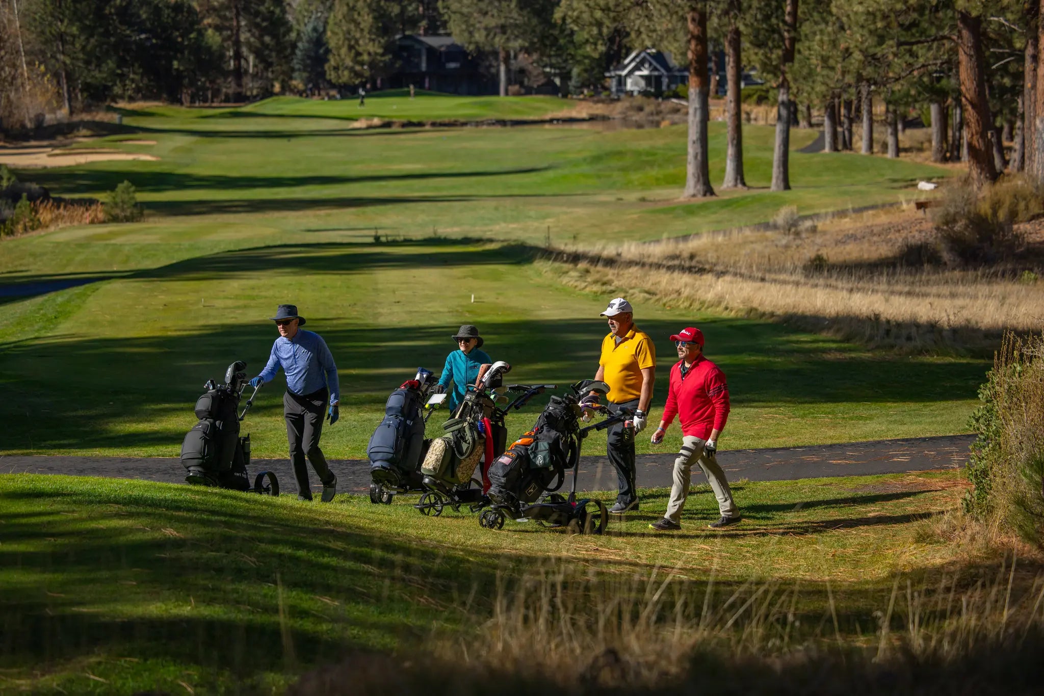 Golfers walking the course while their remote-controlled electric golf caddies carry their bags